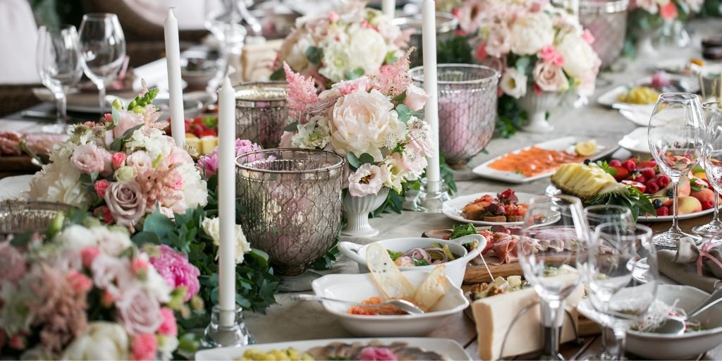 Elegant wedding table setup with floral centerpieces, candles, and gourmet food display.